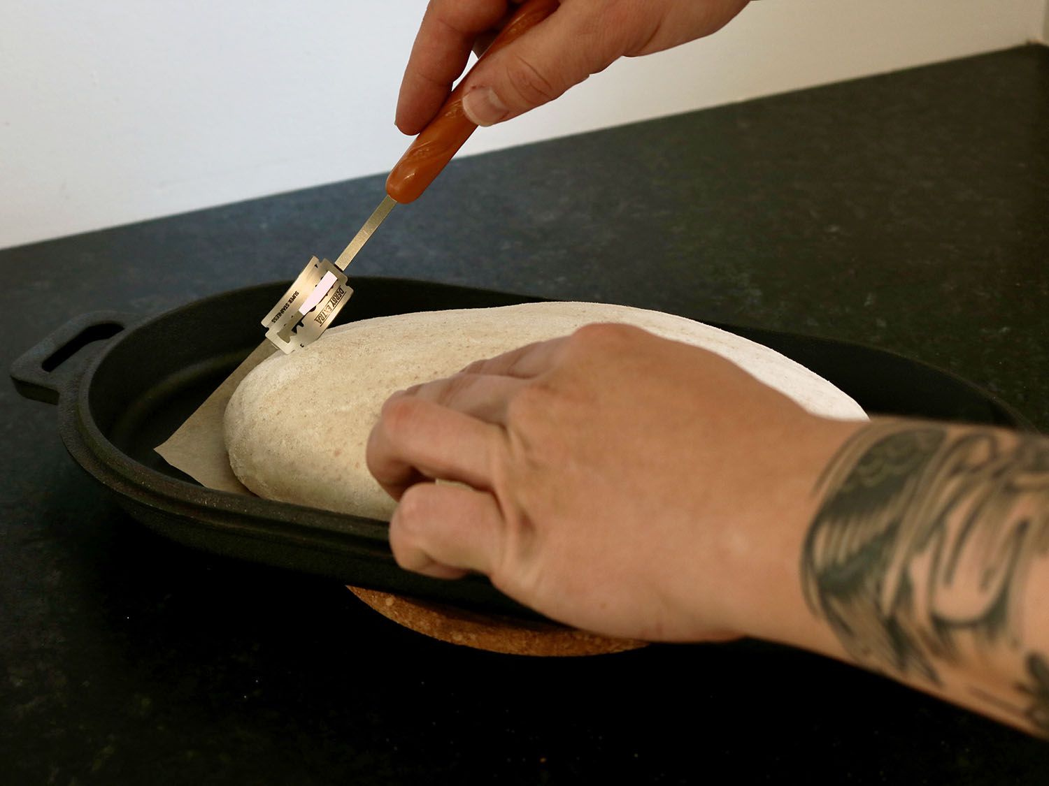 一个面包团正被绑在面包腿上的刀片割开。