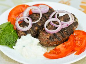 希腊biteki与番茄片、红洋葱片、薄荷叶和tzatziki一起放在盘子里。