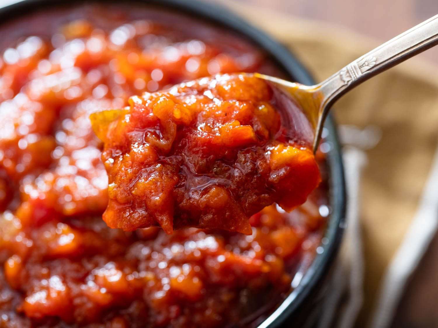 Cooked down even further, obe ata becomes thick and dip-like. Here it is shown in a chunkier style lifted on a spoon, palm oil glistening around its edges.