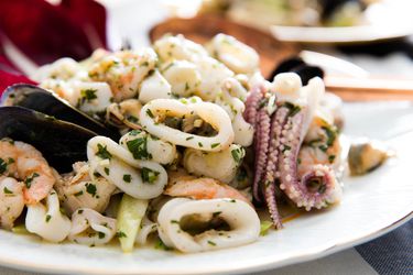 Italian seafood salad with calamari, scallops, shrimp, and mussels on a white plate.