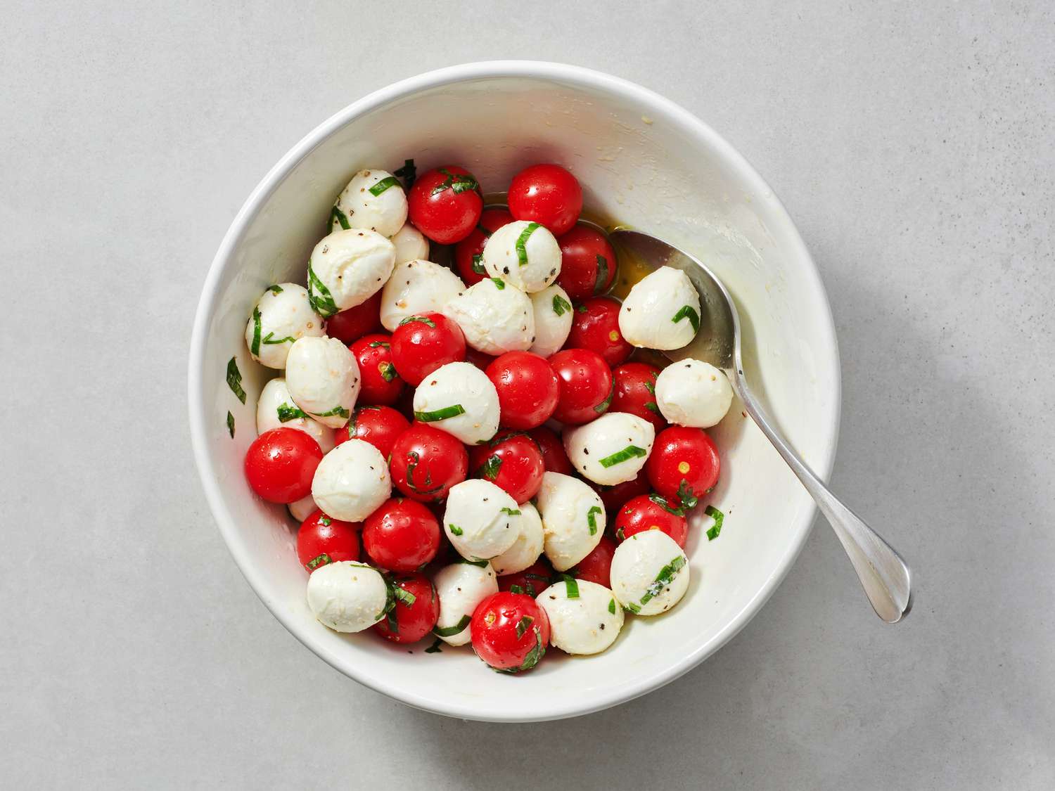 Tomatoes and vinegar tossed with mozzarella mixture mixture inside bowl