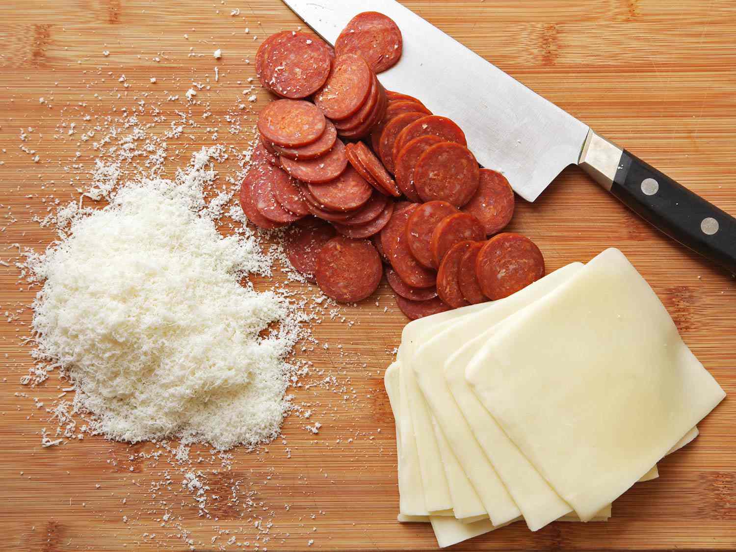 Toppings for Sicilian-style pizza: ground Pecorino, pepperoni, and sliced mozzarella cheese.
