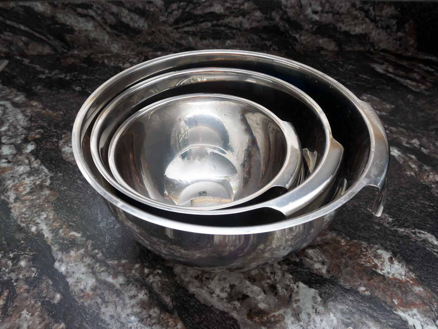 all clad bowls on a black marble surface