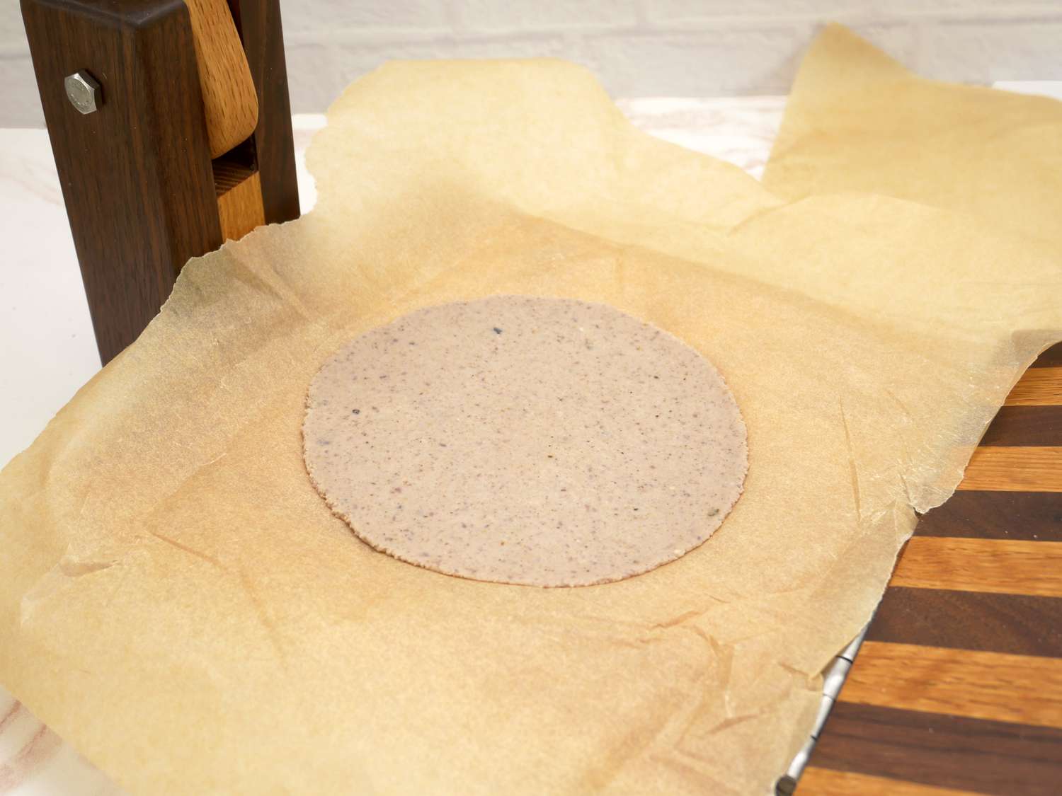 a freshly pressed tortilla in a wooden tortilla press