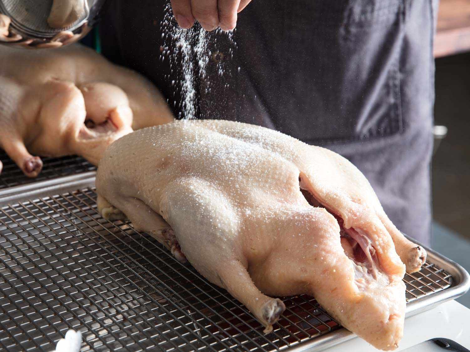 在烤架上撒上盐的生鸭子
