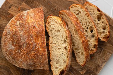 Sliced no-knead bread on a wooden cutting board.