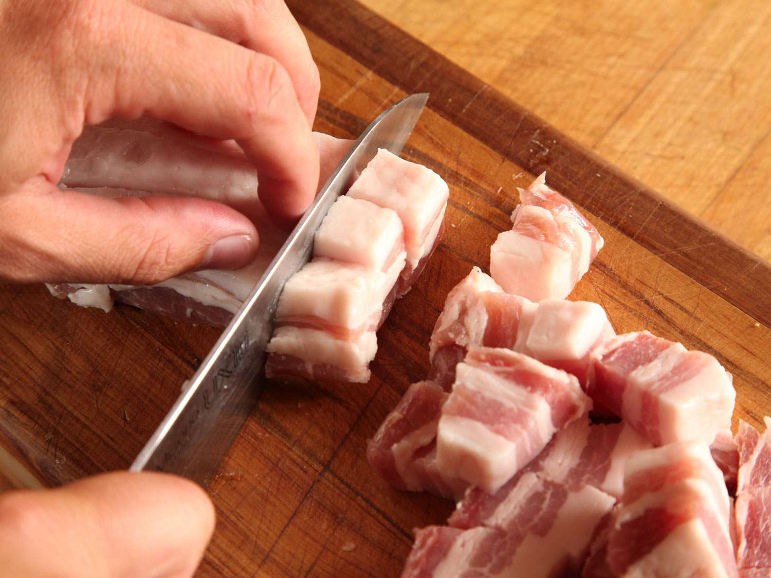 Cutting pork belly into cubes for cassoulet.