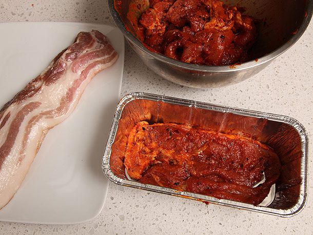 将未煮熟的卤猪肉和生培根分层放入铝制面包锅中。