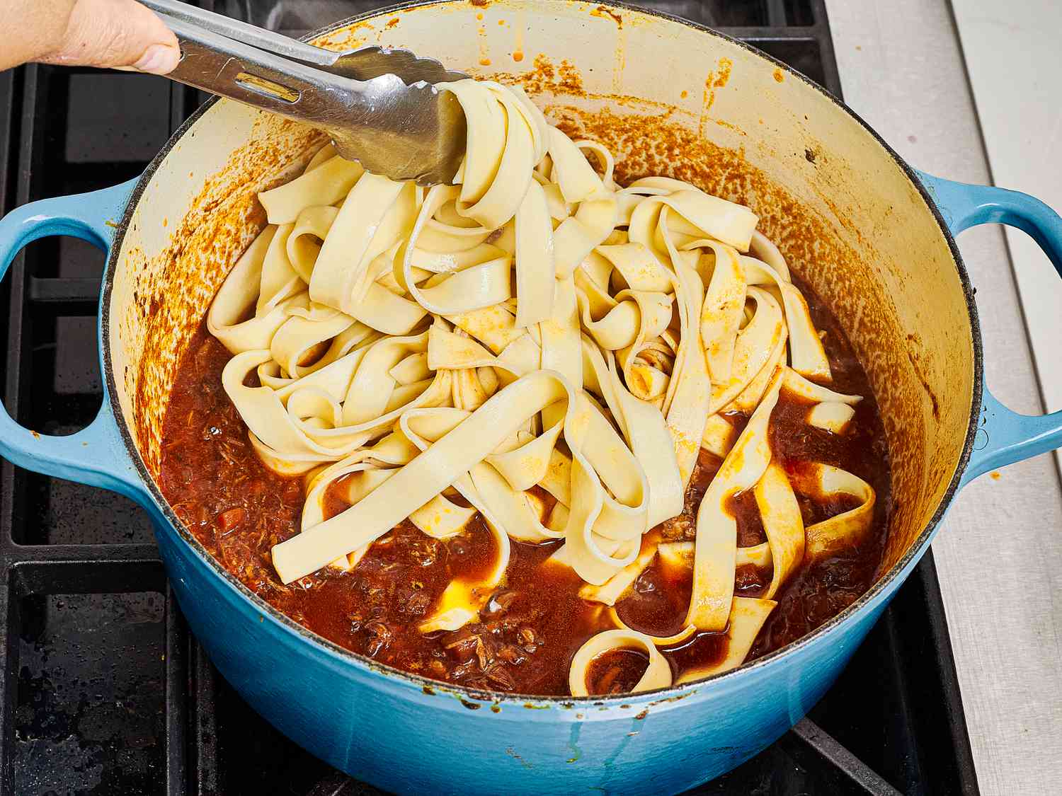 Adding pappardelle pasta to ragu