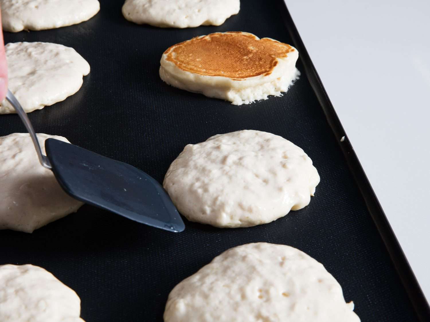 Flipping pancakes on an electric griddle.