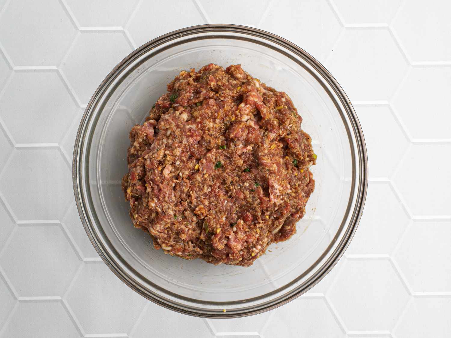 Ground pork, ground beef, hoisin sauce, soy sauce, ginger, garlic, minced scallion, honey, panko breadcrumbs, lightly beaten egg, and freshly ground black pepper mixed together until blended inside a large glass mixing bowl.