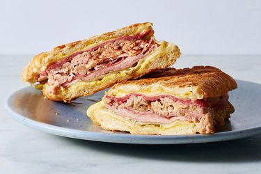 Two cut Cuban sandwiches resting on a plate