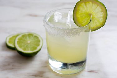 A classic margarita in a rocks glass with salt and a lime wheel on the rim.