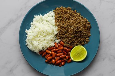 SalpicÃ，白米饭，红芸豆，一片酸橙，放在大理石柜台上的蓝色盘子里。