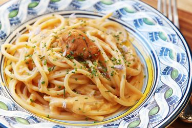 A shallow bowl of creamy sea urchin (uni) pasta with a tongue of sea urchin on top.