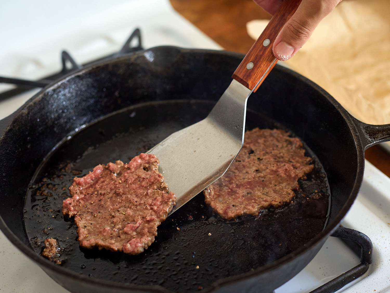 偏移金属特纳从铸铁煎锅中举起一个碎汉堡。