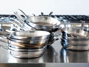 Stacks of stainless-steel skillets sit on a countertop.