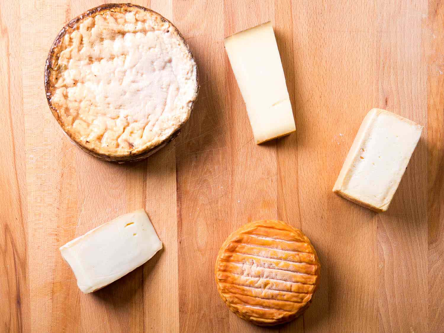 a variety of cheeses on a wooden board