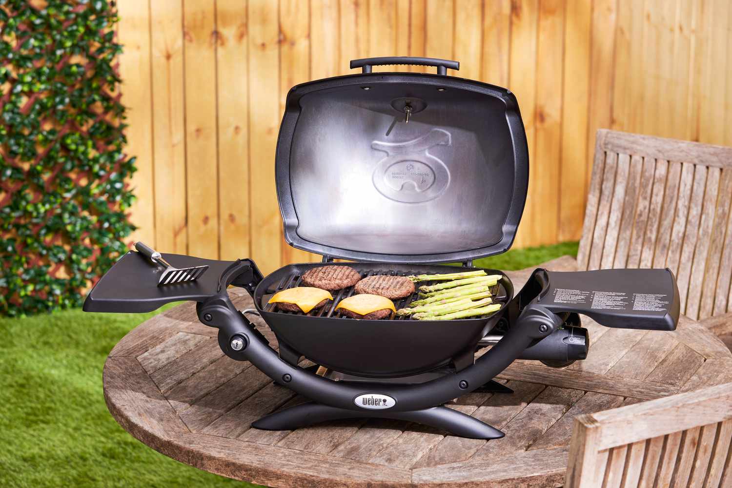 A black portable gas grill on a wooden table