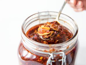 Homemade spicy chili crisp being spooned out of a jar