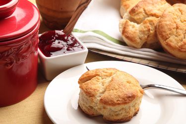 Golden brown 2-ingredient biscuits next to a container of jam