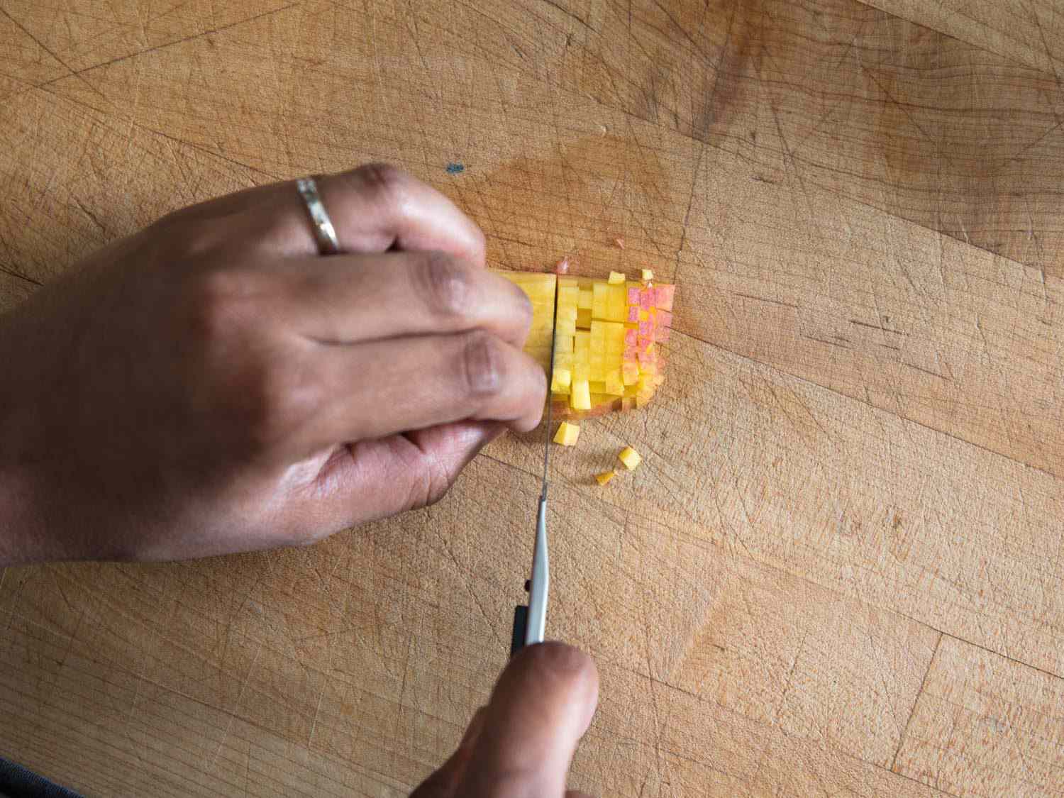 用一把美工刀在砧板上把苹果切成小块