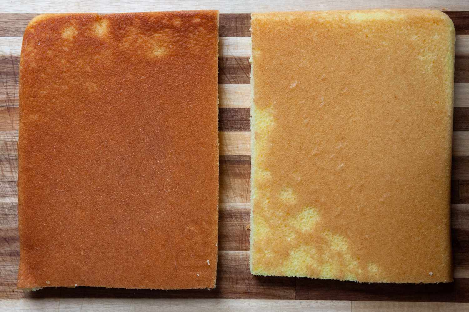 Two slabs of sheet pan cakes, one made in a darker pan is darker than the other.