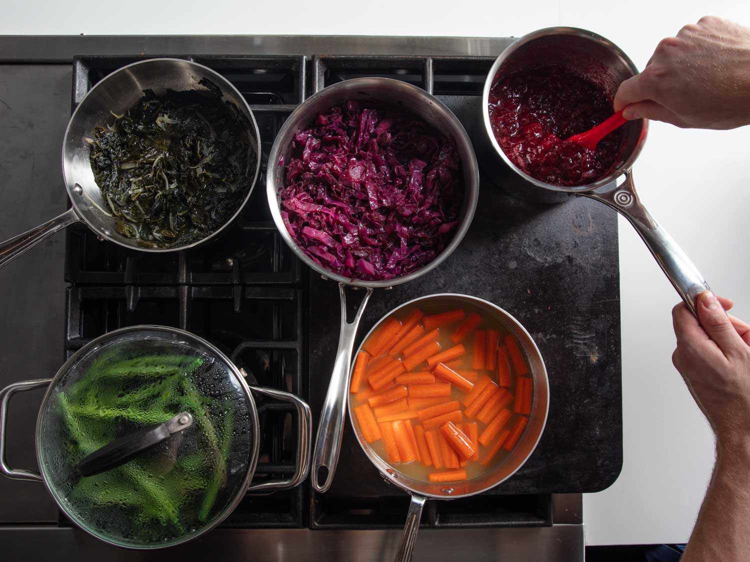 在一个煤气灶的两个燃烧器上设置的烤炉的俯视图，各种各样的蔬菜炖锅在同一时间烹饪。