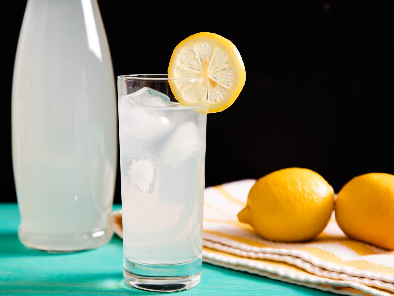 一杯柠檬水，用楔形柠檬装饰一下。背景是一罐柠檬水。gydF4y2Ba
