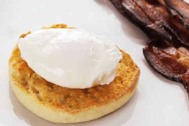 Perfectly poached egg resting on a toasted, buttered English muffin halve