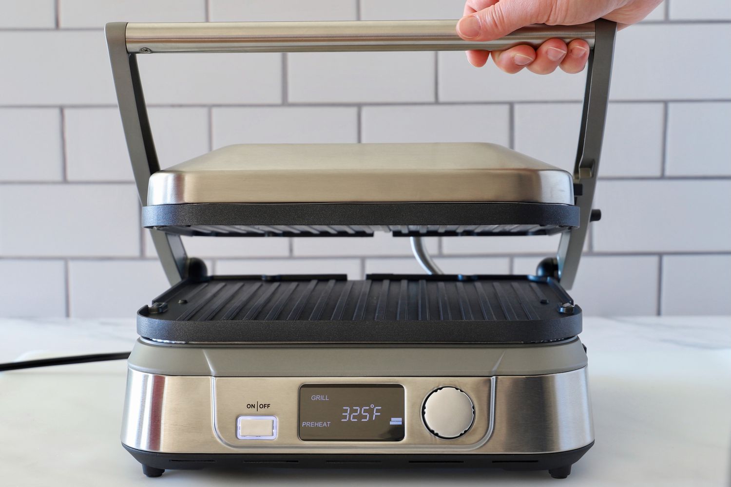 a person opening the lid of a panini press