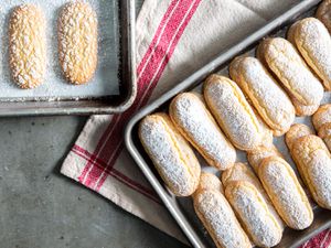 Two parchment-lined sheet pans with one-bowl ladyfinger cookies.