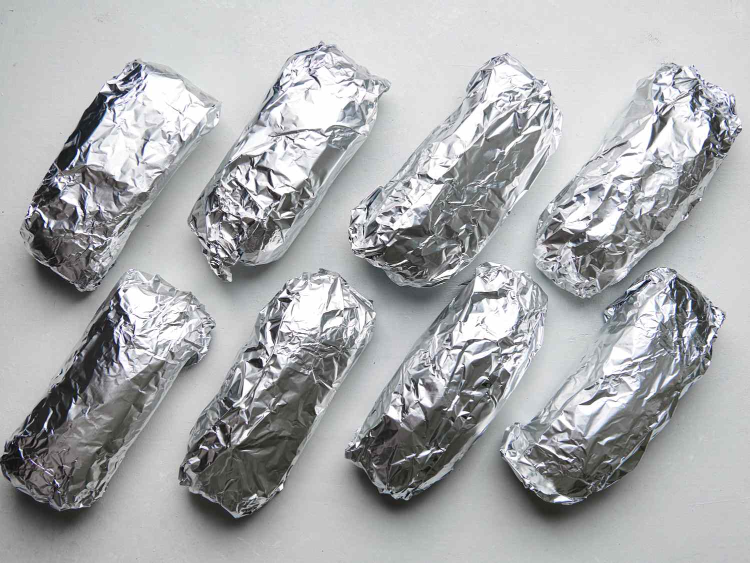 Eight heated sandwich rolls wrapped in aluminum foil.