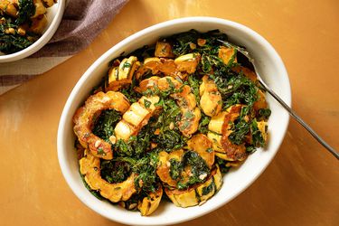 A serving platter of roasted delicata squash and kale salad