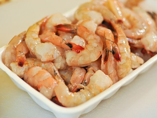 Raw shrimp in a white rectangular bowl.
