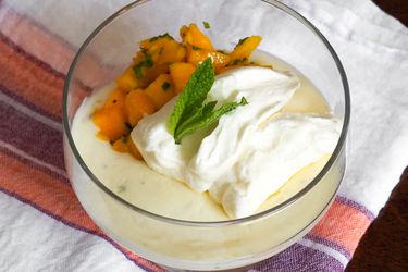 青柠牛乳配薄荷芒果水果沙拉，盛于玻璃碟中，薄荷叶和鲜奶油在上面。