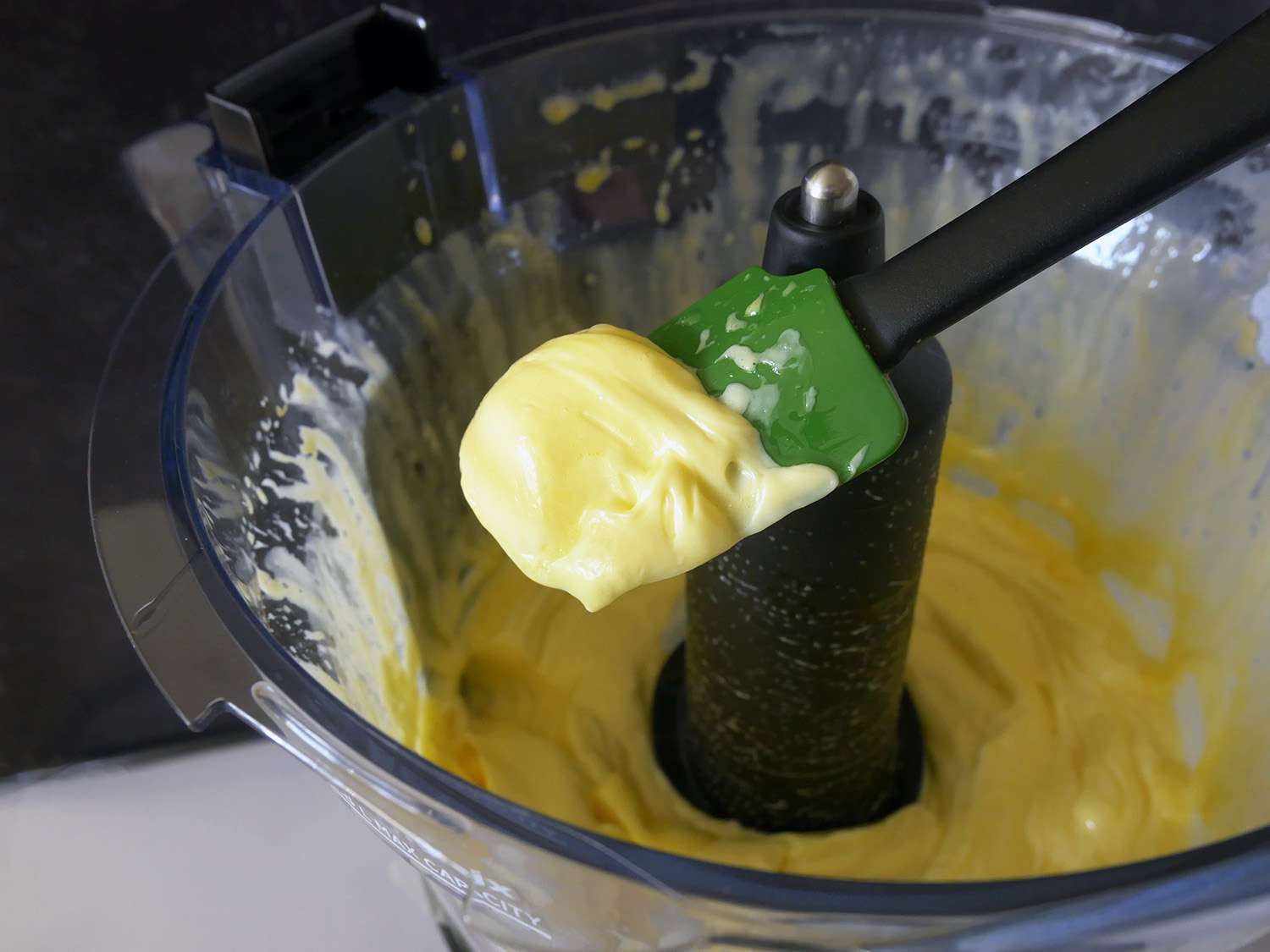 一个特写镜头，铲子铲蛋黄酱从维生素食品加工机。