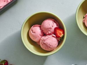 三勺草莓冰淇淋放在陶瓷碗里，外加半个新鲜草莓。