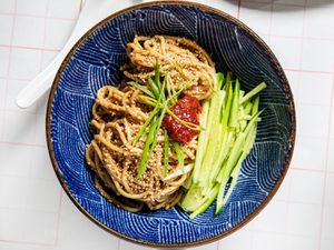 Sesame Noodles with chili paste, cucumbers, and scallions in a blue bow with a wavy patterm