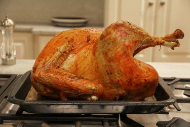 A cooked Grassland Beef Pasture Raised Turkey cools on a baking pan.