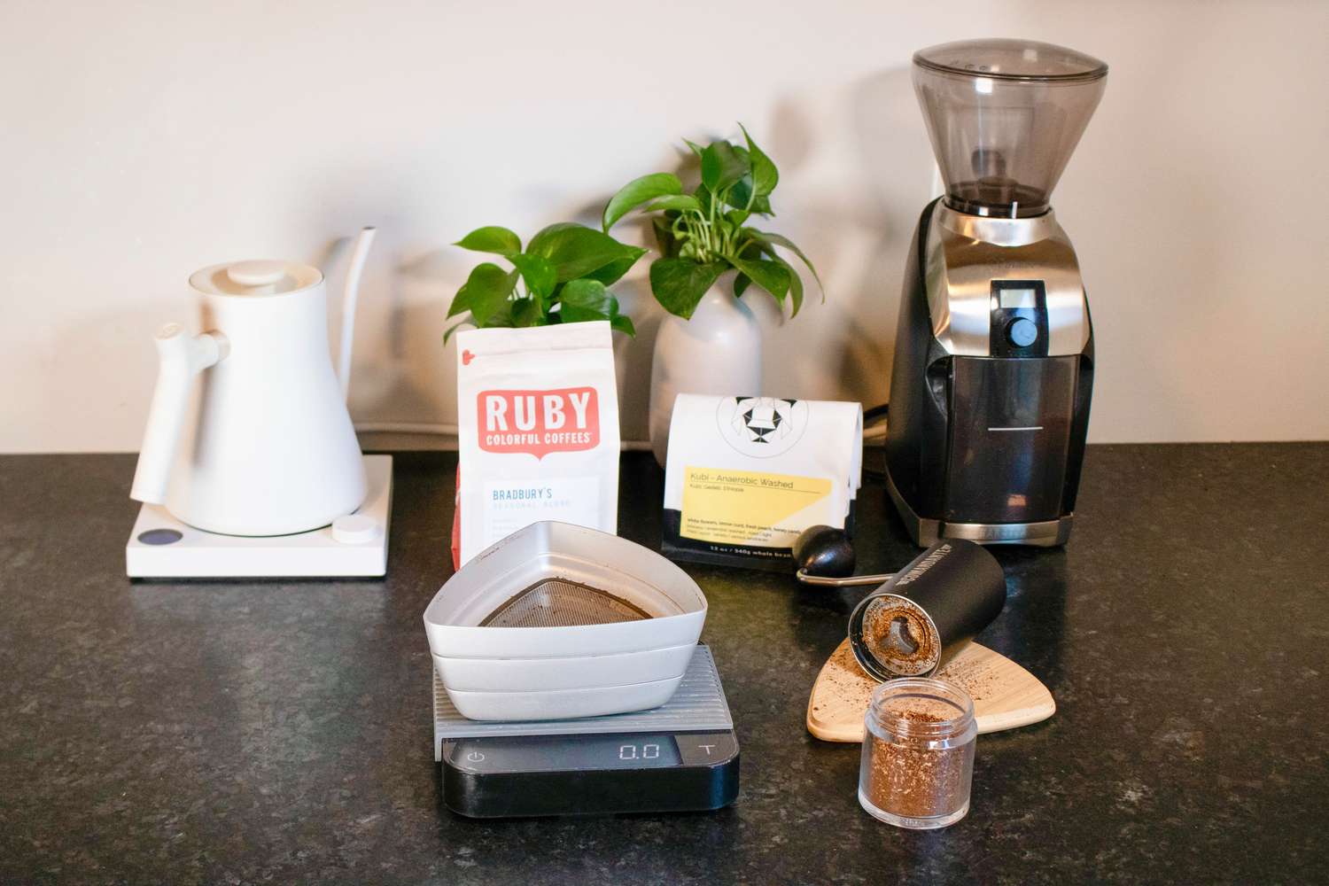 一个手持式咖啡研磨机摆在咖啡筛、水壶和电动研磨机旁边
