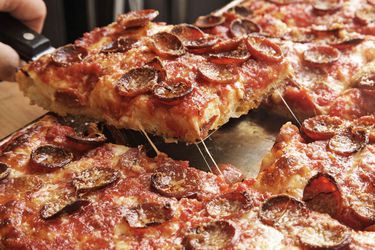 Removing a slice of pepperoni-topped Sicilian pizza from sheet pan.
