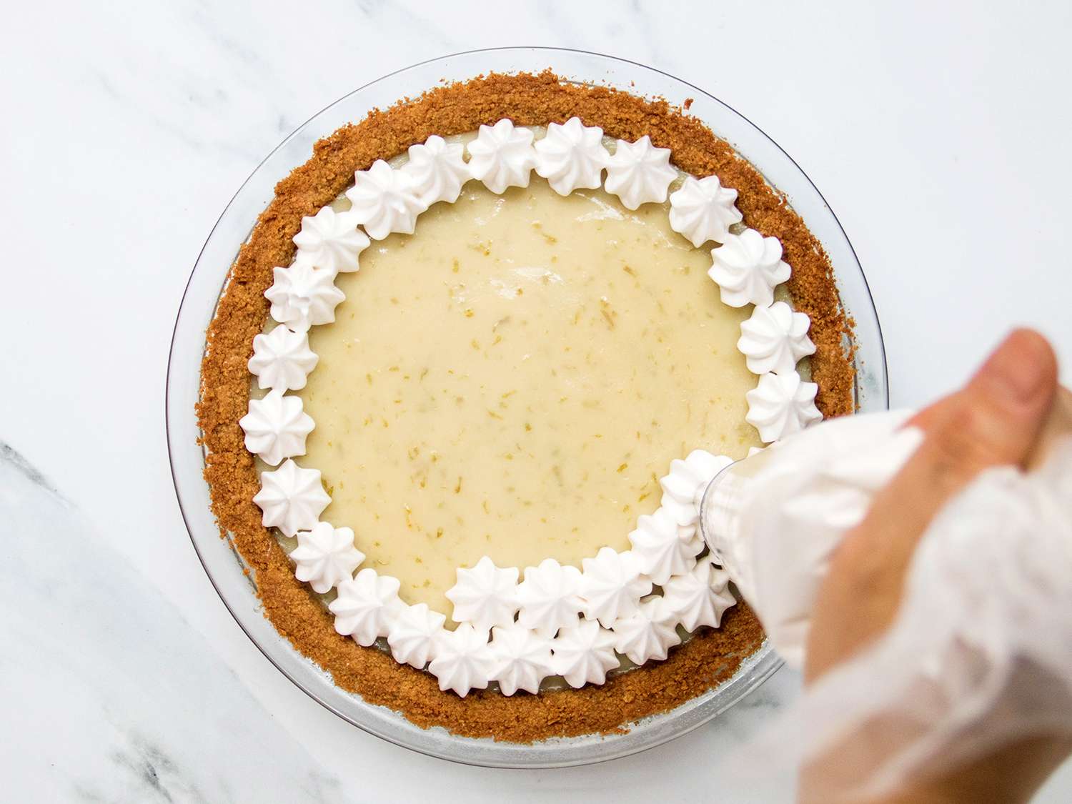 Meringue stars being piped onto top of vegan Key lime pie