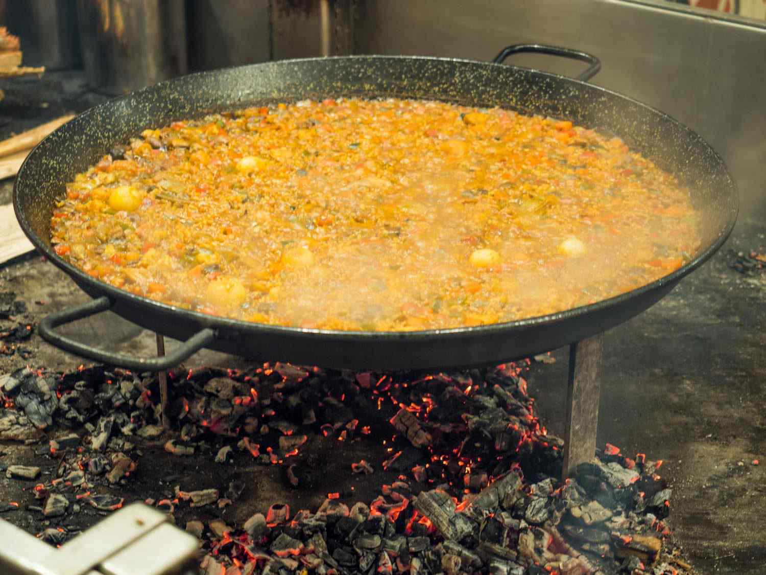 在纽约的小西班牙梅尔卡多，一份巨大的蔬菜海鲜饭正在余烬上完成。海鲜饭锅被高高托起在一个铁架上，这样厨师就很容易控制下面的火和余烬。gydF4y2Ba