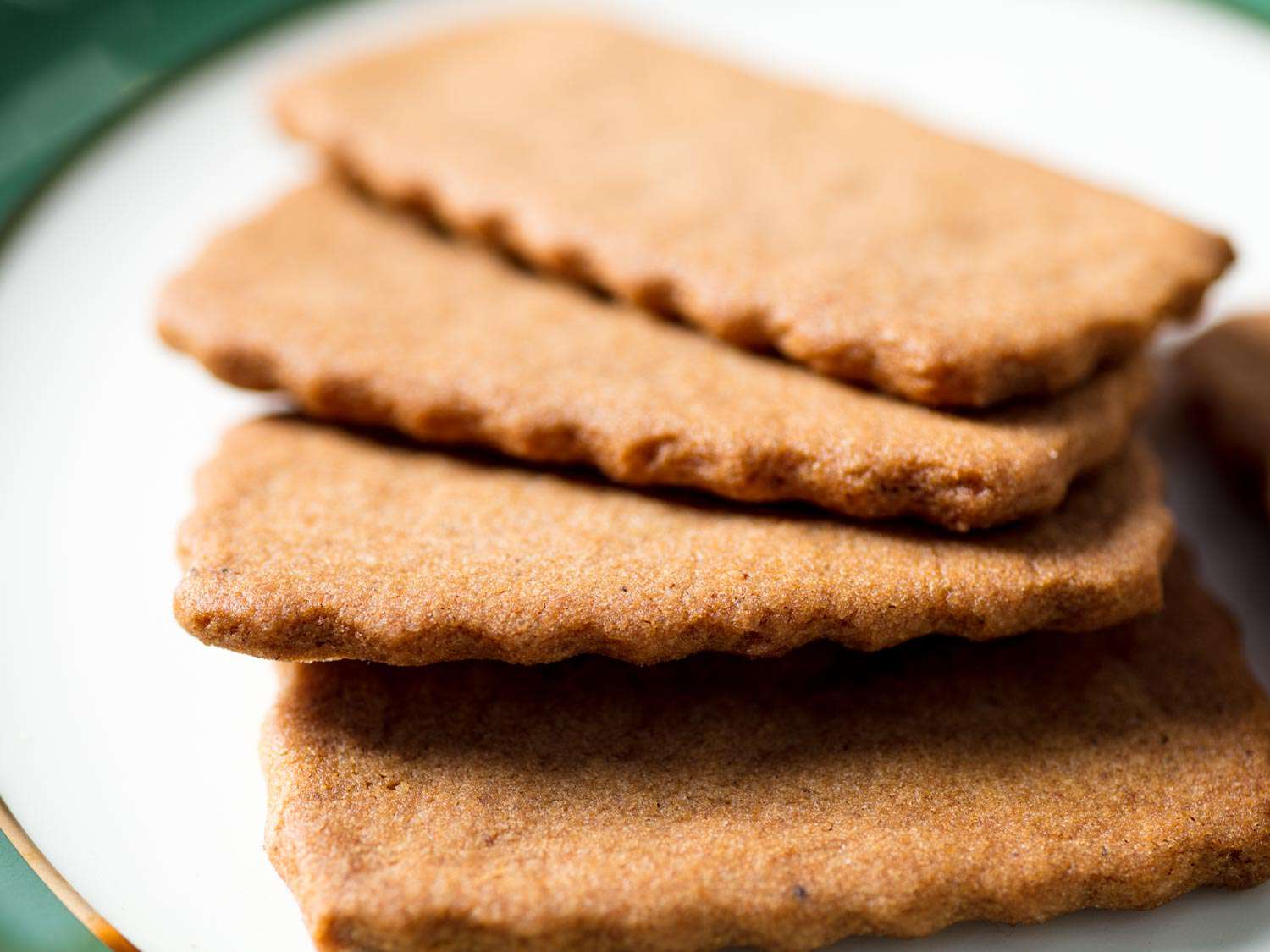 一叠自制的Biscoff或speculoos饼干，放在一个金边和绿色边缘的小盘子里。gydF4y2Ba