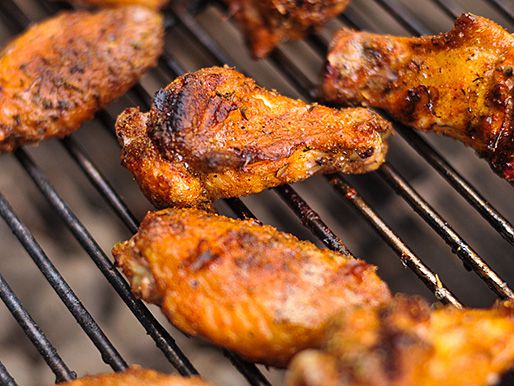 特写的调味翅膀在烧烤格栅，看起来脆和浅棕色。