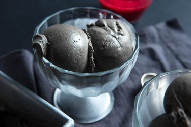 two scoops of black sesame ice cream in glass coupe