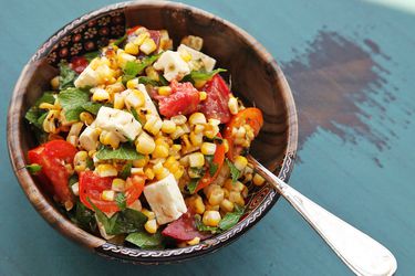 bowl of grilled corn, tomato, and feta salad with herbs
