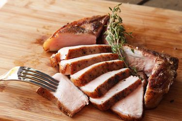 Sous vide bone-in pork chop, sliced, on a cutting board