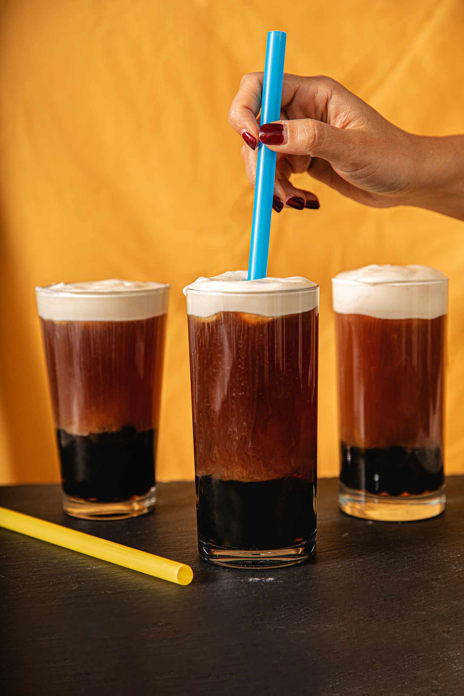 A hand putting a straw into the cheesefoam bubble tea